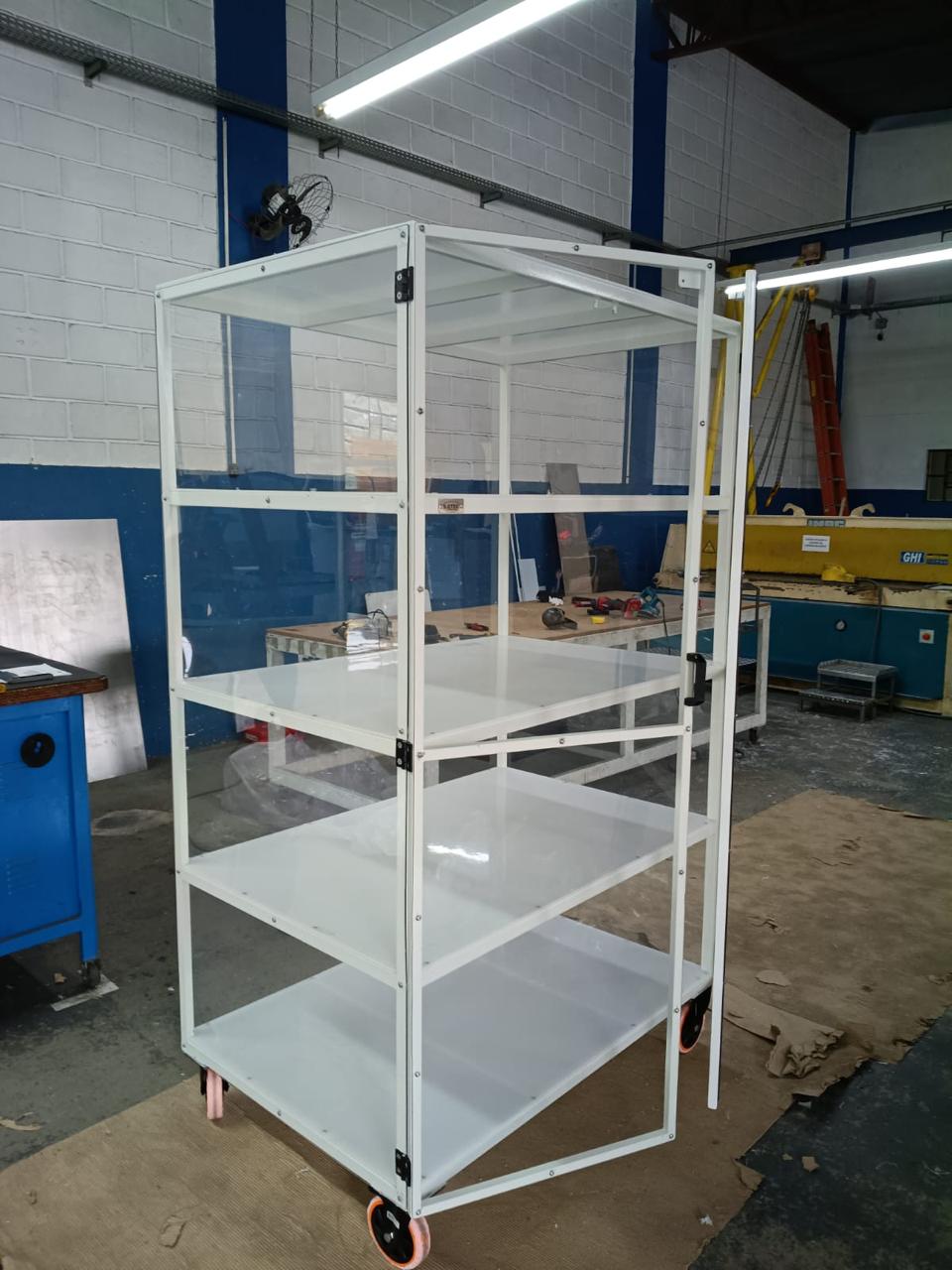 Carrinho branco com prateleiras, painéis transparentes e uma porta aberta