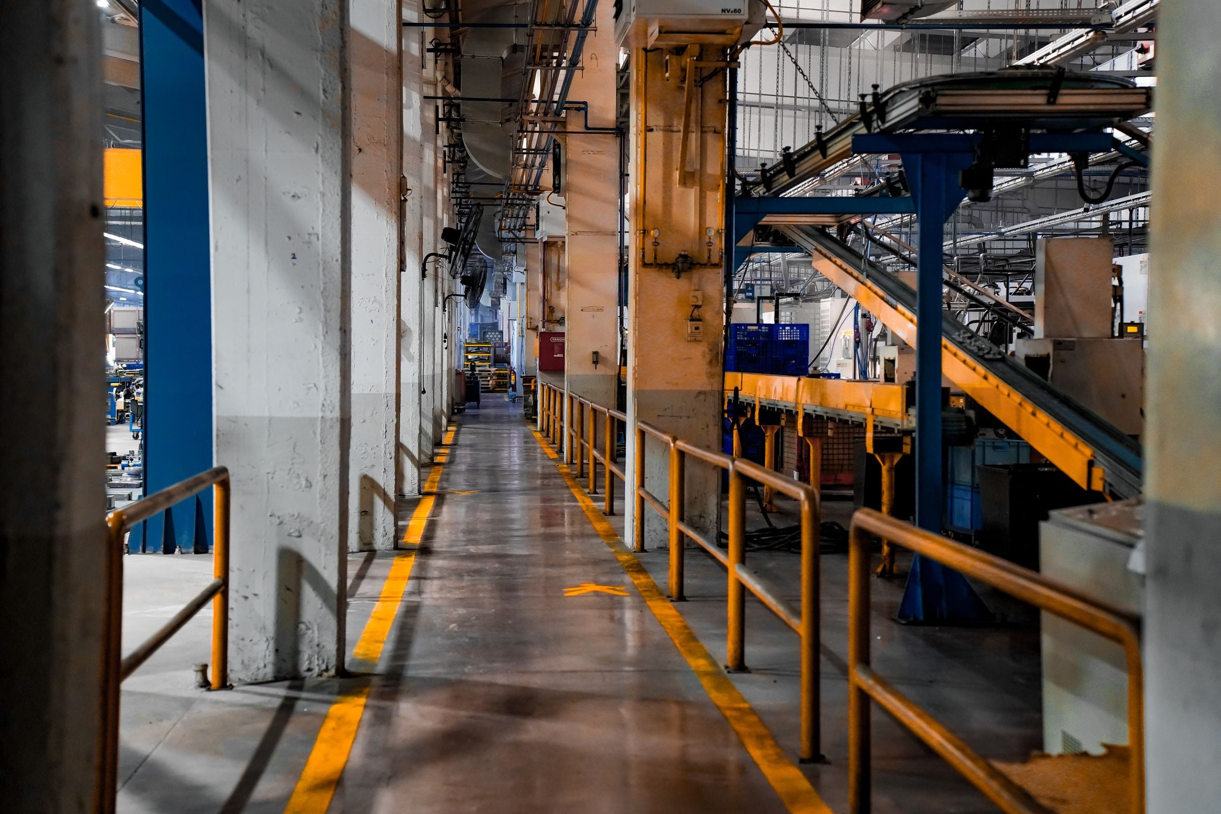 Interior de uma fábrica com máquinas e estruturas metálicas.